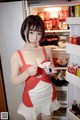 A woman in a red and white dress standing in front of a refrigerator.