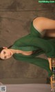 A woman in a green dress sitting on a chair.