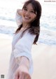 A woman in a white dress standing on a beach.