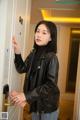 A woman in a black leather jacket is opening a door.