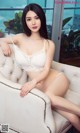 A woman in a white lingerie sitting on a white chair.