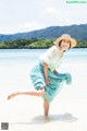 A woman in a straw hat is running on the beach.