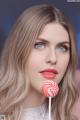A woman holding a lollipop in front of her face.
