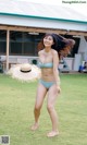 A woman in a blue bikini and a straw hat.